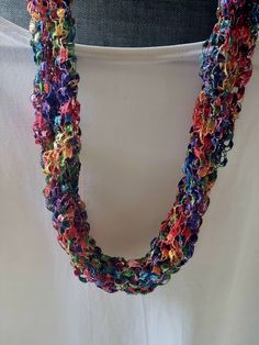 a multicolored crocheted necklace is displayed on a mannequin