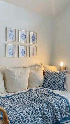 a bed with blue and white sheets, pillows and pictures on the wall above it