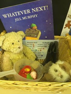 a basket filled with toys and books on top of a table next to a stuffed animal