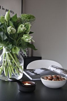 a vase filled with flowers sitting on top of a table next to a bowl of nuts