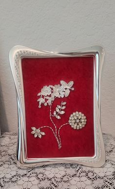 This one of a kind jewelry art framed, flowers with silver jewelry is hand made from vintage rhinestone jewelry and modern rhinestone jewelry pieces in a silver frame with a rhinestone decor and a red velvet background.  Measures  8"x6". Can be displayed all year. Beautiful piece for your Christmas decor, table or mantle.    BoxF Due to the higher cost for shipping is that I take special care in packing to prevent breakage or damage and the size of box. Please look at all pictures and ask questions  before purchase.  I do not accept returns and all sales are final. I ship all packages USPS from Pinehurst, Texas. 77362 I do not ship international. USA ONLY Buyer to pay all shipping cost. Unless listed as free shipping. In case of any delays, damaged or lost packages it is the buyers respons Jewelry Shadow Box Display, Red Velvet Background, Jewelry Shadow Box, Making Frames, Jewelry Art Framed, Christmas Decor Table, Framed Flowers, Velvet Background, Jewelry Pictures