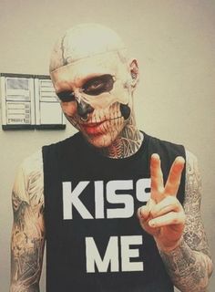 a man in a tank top with a skeleton face painted on his chest holding up the peace sign