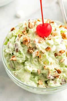 a close up of a salad in a bowl with a cherry on the top and pecans