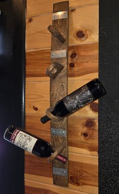 two bottles of wine are hanging on the wall next to a bottle opener and holder