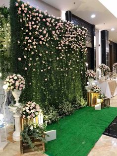 an artificial wall with flowers and greenery in the middle of a room at a wedding reception