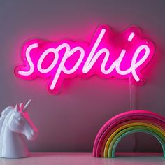 a neon sign that says sophi with a unicorn next to it and a rainbow in the background