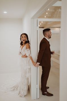 a bride and groom standing in front of a doorway holding each other's hands