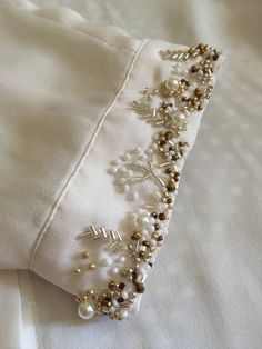 a close up of a white shirt with pearls and beads on the collarline,