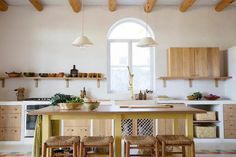 a kitchen with wooden cabinets and stools next to an island in front of a window