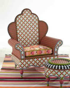 an upholstered chair and foot stool on a multi - colored striped area rug