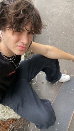 a young man sitting on the ground with headphones in his ears