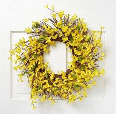 a wreath with yellow flowers hanging on a white door