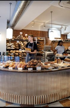 a woman standing behind a counter in a bakery