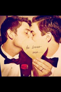 two men in tuxedos kissing each other with the words he loves me written on his heart