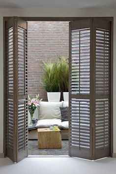 an open door leading to a living room with white furniture and potted plants in the corner