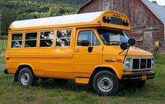 an old yellow school bus parked in front of a barn