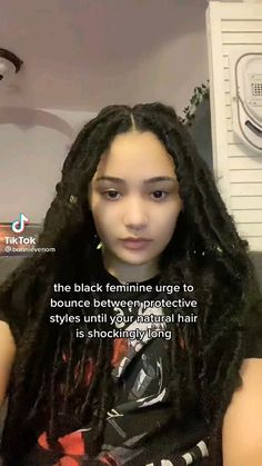 a woman with long dreadlocks sitting in front of a hair dryer and looking at the camera