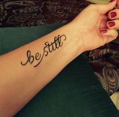 a woman's wrist tattoo with the word be still written on her left arm