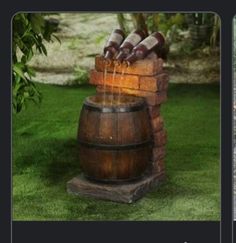 a wooden barrel filled with water on top of a lush green field next to a brick wall