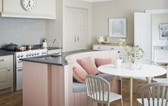 a white table and chairs in a small room next to a kitchen with an island