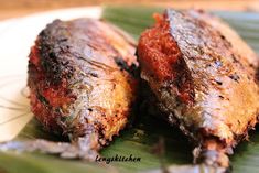 two pieces of cooked fish sitting on top of a green leaf