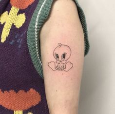 a woman's arm with a small cartoon character tattoo on the left upper arm