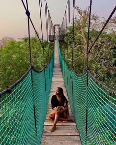 a woman sitting on the end of a suspension bridge