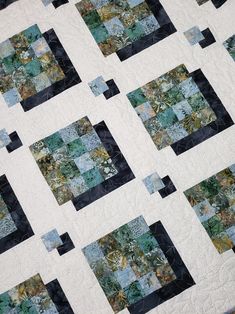 a quilt made with squares and flowers on top of a white tablecloth covered in black strips