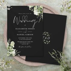 two black wedding cards with white flowers on them