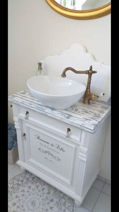 a white sink sitting under a mirror next to a counter top with a gold faucet