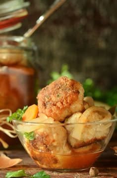 a bowl filled with food sitting on top of a wooden table next to a jar