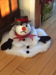 a snowman sitting on top of a pile of fluffy white fur next to a door