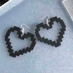 two pairs of black earrings sitting next to each other on top of a gray surface