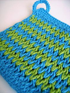 a blue and green crocheted bag sitting on top of a table