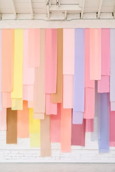 colorful ribbons hanging from the ceiling in front of a white brick wall