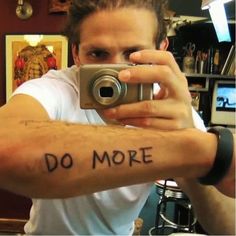 a man taking a selfie with his camera in front of him that says do more