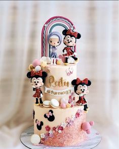 a three tiered cake decorated with mickey and minnie mouse figurines