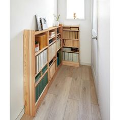 a book shelf filled with lots of books on top of a hard wood floor next to a window