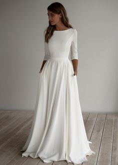 a woman in a white dress standing on a wooden floor with her back to the camera