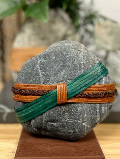 a rock with two leather bracelets on it sitting on top of a wooden stand