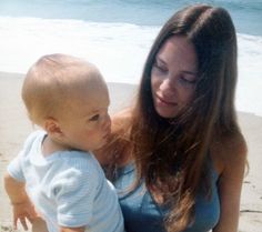 a woman holding a baby on the beach