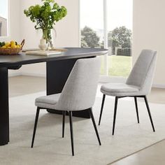 a dining room table with two chairs and a bowl of fruit on the table next to it