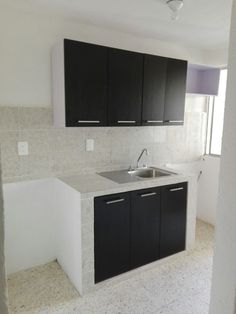 an empty kitchen with black cabinets and white counter tops