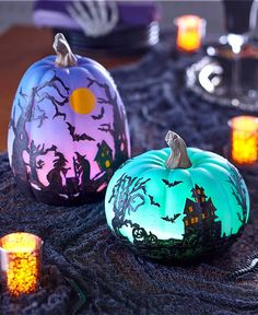 two painted pumpkins sitting on top of a table next to candles and other decorations