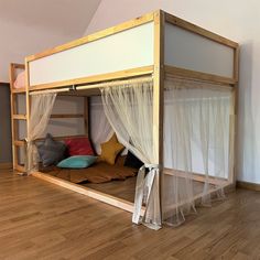 a bunk bed with mosquito netting on the top and bottom, in a room with hardwood floors