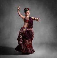 a woman in a colorful dress is dancing with her arms spread out and hands raised