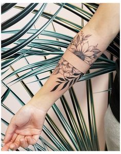 a woman's arm with a flower tattoo on her left hand and a wrist band