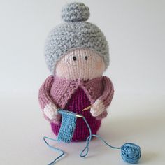 a knitted doll is holding a ball of yarn