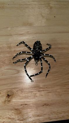 a black and white spider sitting on top of a wooden table