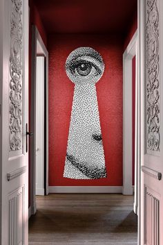 an open door leading to a hallway with a painting on the wall and a red background